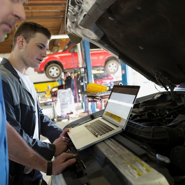 Mechanics with laptop performing engine diagnostics