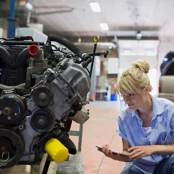 Female mechanic with digital tablet examining engine