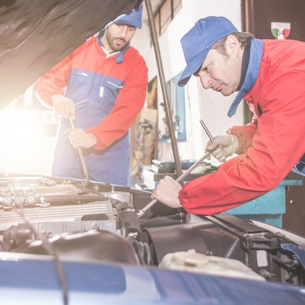 Two mechanics working on a car