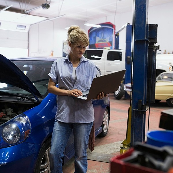 Female mechanic using laptop in auto repair shop